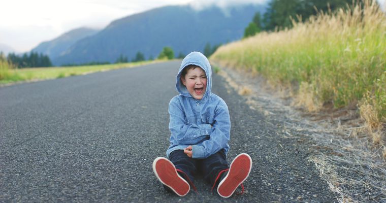 A boy having a temper tantrum in the road