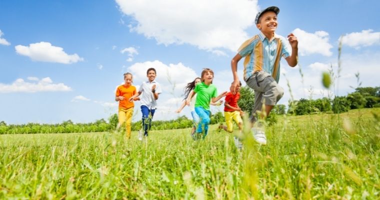 Happy children running through a field on a sunny day.