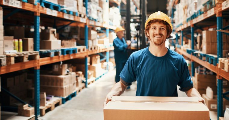 A guy holding a box in a warehouse