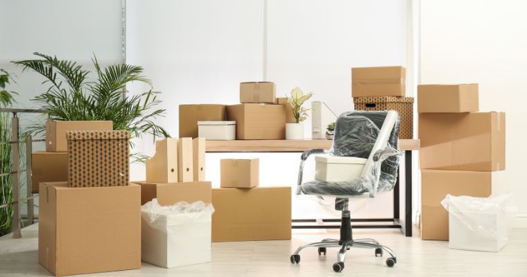 Cardboard boxes and office chair packed up ready for a business move.