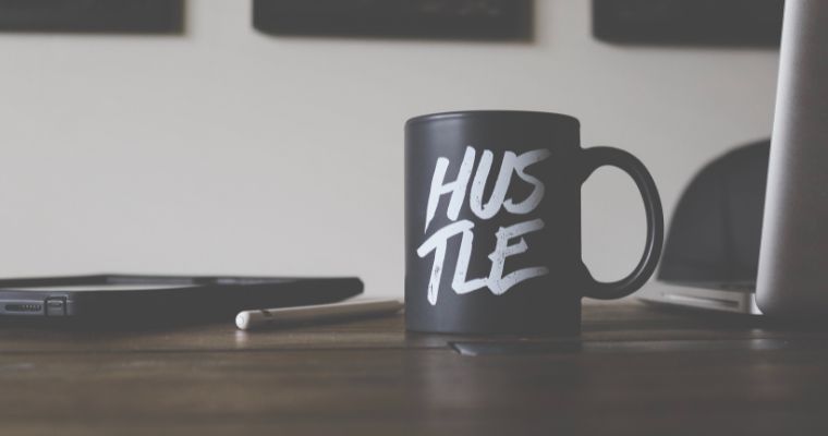 A cup with 'hustle' printed on the side of it.