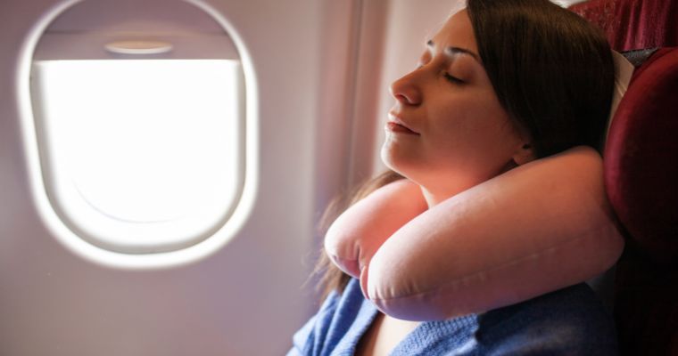 A woman using a neck pillow on a plane