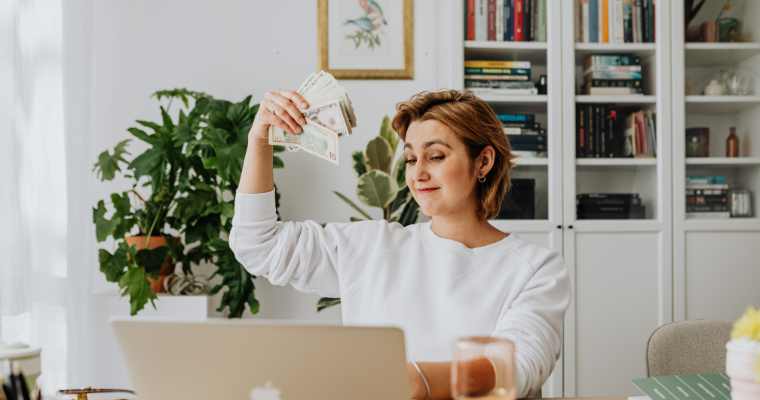 woman working on laptop waving cash around